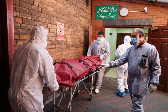 Workers wearing protective equipment transport a body in the grounds of the Central Jamia Mosque Ghamkol Sharif, a temporary morgue set up at a Mosque as the spread of the coronavirus disease (COVID-19) continues, Birmingham, Britain, April 21, 2020. (Photo by Carl Recine/Reuters)