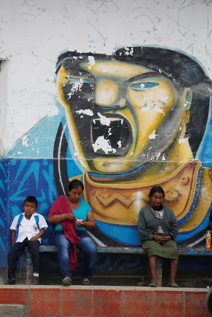 People sit next to a mural in Toribio, Cauca, Colombia, February 9, 2016. (Photo by Jaime Saldarriaga/Reuters)