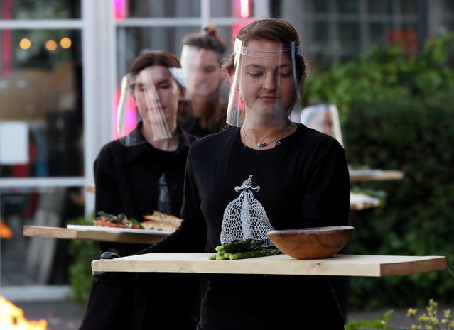 Servers in protective gear carry food at a restaurant which is testing servers providing drinks and food to models pretending to be clients in a safe “quarantine greenhouses” in which guests can dine in Amsterdam, Netherlands on May 5, 2020. (Photo by Eva Plevier/Reuters)