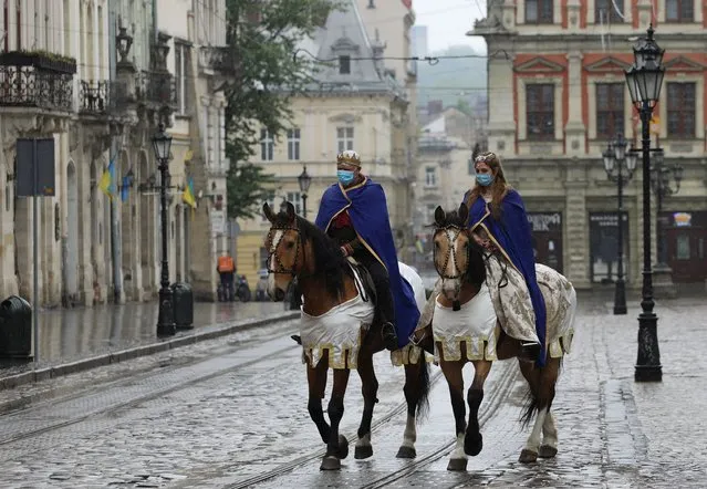 Actors dressed as King Leo and Queen Constance wearing protective masks ride horses along the street as a festive procession marking the City Day was canceled, in Lviv, Ukraine, on May 3, 2020. (Photo by Roman Balun/Reuters)