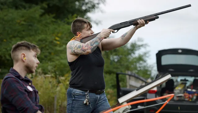 In this October 8, 2017, photo, Jake Allen, left, watches as Lore McSpadden fires at a clay target he released during a training session for the Trigger Warning Queer & Trans Gun Club in Victor, N.Y. McSpadden never touched a gun before the gun club started this past year. (Photo by Adrian Kraus/AP Photo)