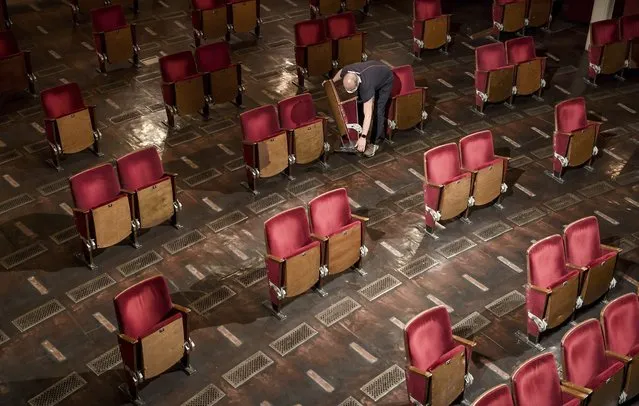 An employee carries chairs from the rows of seats in the auditorium of the Berliner Ensemble on May 27, 2020. Due to the contact restrictions during the corona pandemic, individual seats will be removed for future performances. (Photo by Britta Pedersen/dpa-Zentralbild/dpa)