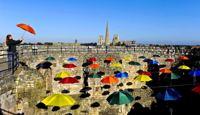 Louise Wyatt stands in a new art installation called 'Umbrella Sky' inside Clifford's Tower, York in England, on October 9, 2012. The installation is a light hearted look on the recent bad weather suffered by the city. It is the first time the medieval tower has had any kind of covering since an explosion blew off the roof in 1684. (Photo by Anna Gowthorpe/PA Wire)