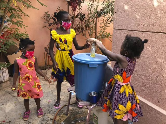 In this May 21, 2020, photo, the Larson sisters wash their hands inside the gate at their home in Dakar, Senegal. The girls were adopted from Sierra Leone after their father and other relatives died of Ebola. (Photo by Krista Larson/AP Photo)