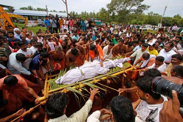 People carry the dead body of Babiya, a crocodile at Ananthapura lake temple, for its burial at the Ananthapadmanabha Swamy temple at Kasaragod in India's Kerala state on October 10, 2022. (Photo by AFP Photo/Stringer)