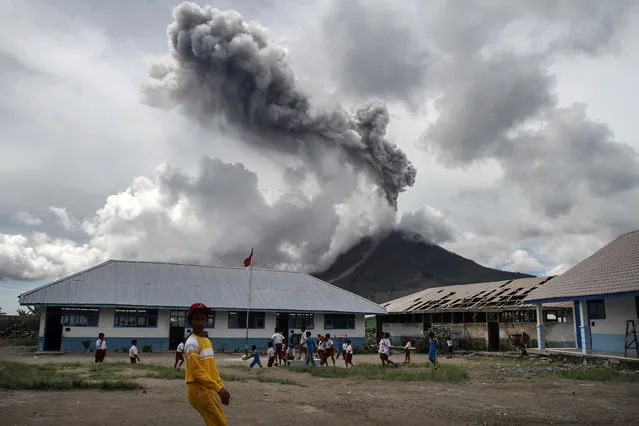 Children play at an elementary school as the Mount Sinabung volcano spews smoke in Karo on November 13, 2017. Sinabung roared back to life in 2010 for the first time in 400 years, after another period of inactivity it erupted once more in 2013, and has remained highly active since. (Photo by Ivan Damanik/AFP Photo)