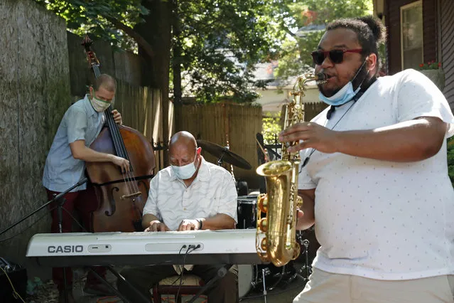 Elijah Herring, right, plays the sax while performing with keyboardist Kenny Barron, center, and bassist Dan Loomis, during Make Music-New York in Brooklyn's Ditmas Park neighborhood during the coronavirus outbreak, Sunday, June 21, 2020, in New York. The concert was one of seven simultaneously performed live jazz, classical and rock performances offered from the driveways, porches and balconies of Victorian homes in the neighborhood. (Photo by Kathy Willens/AP Photo)