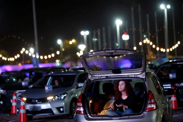 A woman sits inside her car during the performance of the Brasilia Philharmonic Orchestra during the inauguration of the drive-in movie theatre at the parking lot of President Juscelino Kubitschek International Airport Park in Brasilia, Brazil on June 23, 2020. (Photo by Adriano Machado/Reuters)