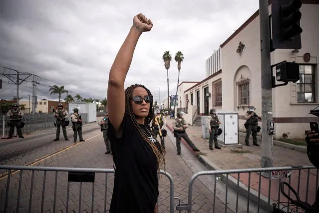 A protester raises her fist facing Los Angeles County Sheriff's deputies during a protest against the death of Andres Guardado in an officer involved shooting, in Compton, California, USA, 28 June 2020. Guardado, 18, was shot and killed by police on 18 June while working as a security guard for an autobody shop in Gardena, California. (Photo by Étienne Laurent/EPA/EFE)