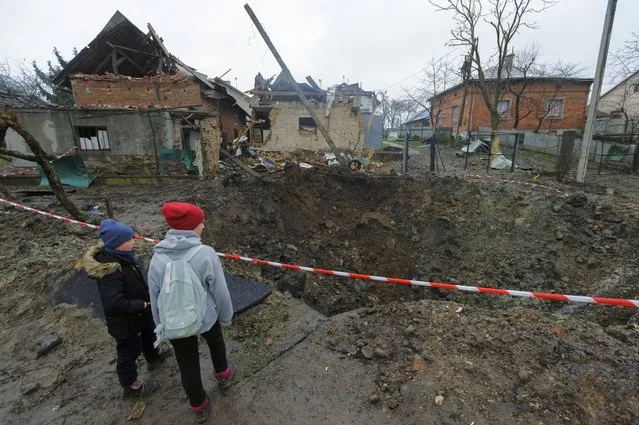 Children look at a crater created by an explosion in a residential area after Russian shelling in Solonka, Lviv region, Ukraine, Wednesday, November 16, 2022. (Photo by Mykola Tys/AP Photo)