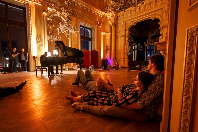 Enthusiasts listen a concert by Italian pianist and performer Marino Formenti, during an opera sleepover event at the Grand Theatre in Geneva on April 5, 2025. Once a year, the Grand Theatre allows a small group of enthusiasts to spend a night, set to music, exploring its majestic halls, admiring its marble entranceway and meandering through fresco-covered foyers. (Photo by Fabrice Coffrini/AFP Photo)