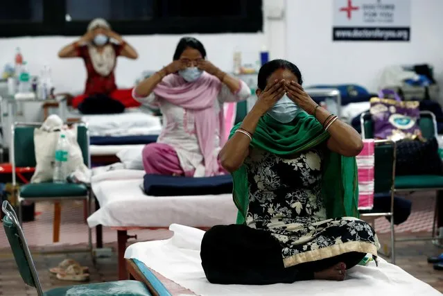 People suffering from the coronavirus disease (COVID-19) perform yoga inside a care centre for COVID-19 patients at an indoor sports complex in New Delhi, July 21, 2020. (Photo by Adnan Abidi/Reuters)
