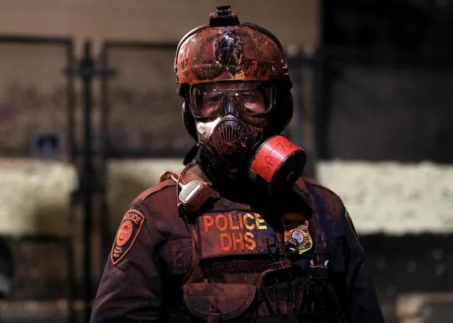 A federal law enforcement officer is covered in red paint during a protest against racial inequality and police violence in Portland, Oregon, U.S., July 26, 2020. (Photo by Caitlin Ochs/Reuters)