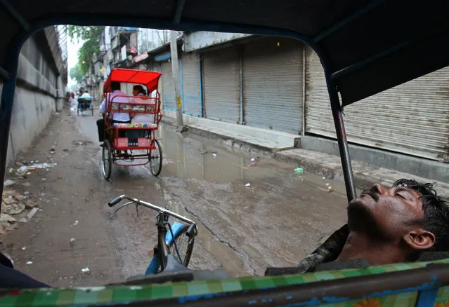 A cycle rickshaw puller takes a nap in front of closed shops during a day-long strike in New Delhi July 5, 2010. (Photo by B. Mathur/Reuters)