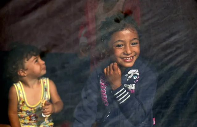 A migrant child smiles as she sits inside a tent close to the border between Serbia and Hungary, near the village of Horgos, Serbia, September 17, 2015. (Photo by Stoyan Nenov/Reuters)