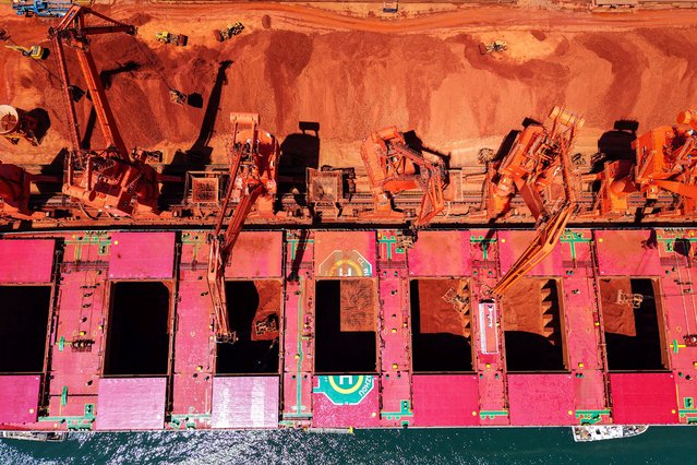 Imported iron ore is unloaded from a ship at a port in Qingdao, in eastern China's Shandong province on April 25, 2025. (Photo by AFP Photo/China Stringer Network)