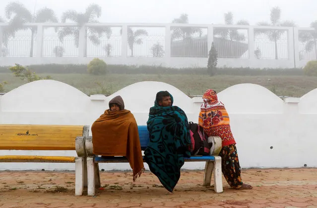 People wrap themselves in blankets and shawls as they wait for trains at a railway station on a foggy winter morning on the outskirts of Agartala, India, January 6, 2018. (Photo by Jayanta Dey/Reuters)