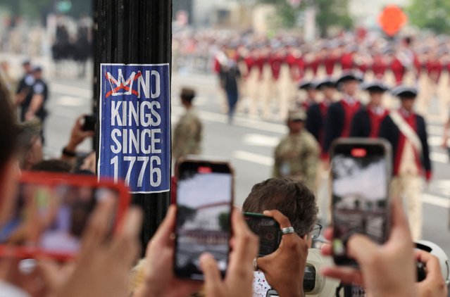 A No Kings sticker stuck on a post as participants in vintage uniforms march past during the parade in Washington on June 14, 2025. (Photo by Jonathan Ernst/Reuters)