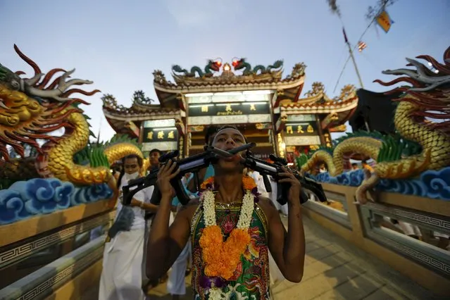 A devotee of the Chinese Ban Tha Rue shrine walks with guns pierced through his cheeks during a procession celebrating the annual vegetarian festival in Phuket, Thailand, October 17, 2015. (Photo by Jorge Silva/Reuters)
