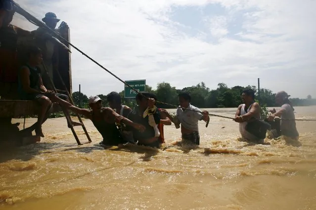 Residents hold on a rope to board a truck while crossing floodwaters brought by typhoon Koppu that battered Candaba town, Pampanga province, north of Manila October 20, 2015. (Photo by Romeo Ranoco/Reuters)