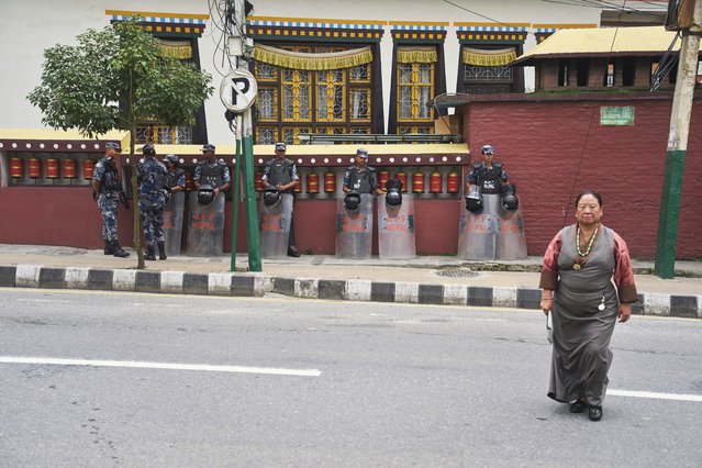 A Tibetan woman crosses a road as Nepalese police stand guard outside the Tibetan Camp during the 90th birthday celebration of spiritual leader the Dalai Lama in Kathmandu, Nepal, Sunday, July 6, 2025. (Photo by Niranjan Shrestha/AP Photo)