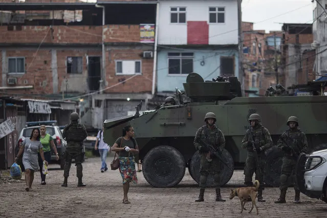 Brazilian marines stand in guard next to an armored vehicle a during surprise operation in Kelson's slum in Rio de Janeiro, Brazil, Tuesday, February 20, 2018. (Photo by Leo Correa/AP Photo)
