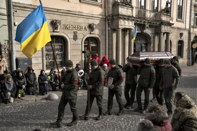 Soldiers carry the coffin of military serviceman Ruslan Zastavnyi during his funeral in Lviv, Ukraine, on Monday, February 20, 2023. Zastavnyi joined the army in March 2022, died two weeks ago near Bakhmut. (Photo by Petros Giannakouris/AP Photo)