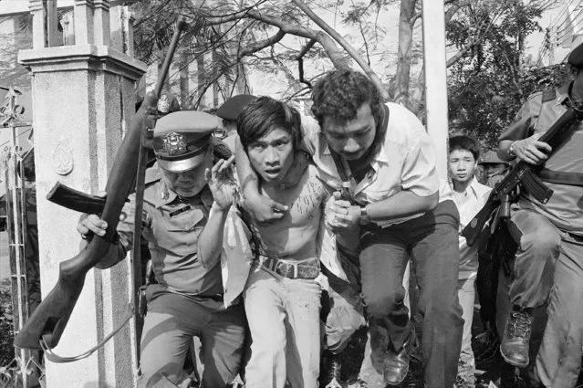 In this October 6, 1976 file photo a captured and wounded leftist student is taken by police to an ambulance in Bangkok, Thailand. (Photo by Neal Ulevich/AP Photo)