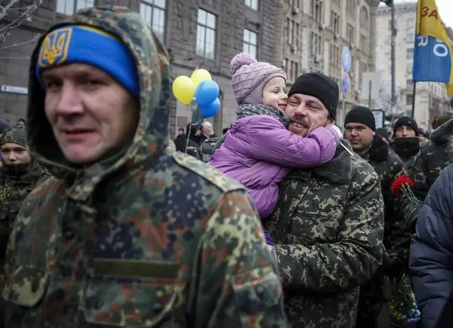 A serviceman of “Kiev 12” military defence battalion holds his daughter as he march on Khreshchatyk street during a welcoming ceremony in Ukrainian capital Kiev December 6, 2014. (Photo by Gleb Garanich/Reuters)