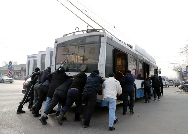 People help to remove a trolley bus from an intersection during a power outage in Bishkek, Kyrgyzstan, 25 January 2022. There is no electricity in the capital of Nur-Sultan, Shymkent, Taraz, Turkestan region, as well as in the capital of Kyrgyzstan – Bishkek, the city of Osh and the city of Tashkent in Uzbekistan. There are also reports of a lack of electricity in Uzbekistan, Kyrgyzstan and the border zone of China. According to preliminary data, an uncontrolled release of radiation-explosive material occurred at the site of the Kok-Borsok energy ring, causing a fire and an explosion. According to experts of Kok-BorsokElectro, the restoration of the damaged section will take from 7 to 10 days. The incident is classified as a terrorist attack. (Photo by Igor Kovalenko/EPA/EFE)