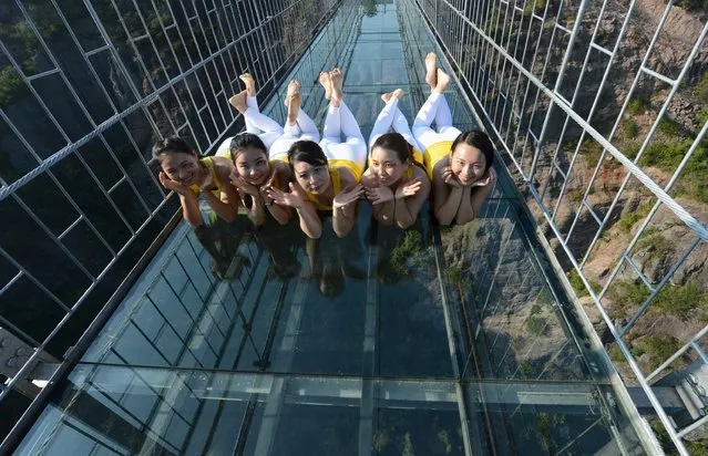 Women pose for pictures after practicing yoga for a performance on a glass bridge at the Shiniuzhai National Geo-park in Pingjiang county, Hunan province, China, November 5, 2015. (Photo by Reuters/China Daily)