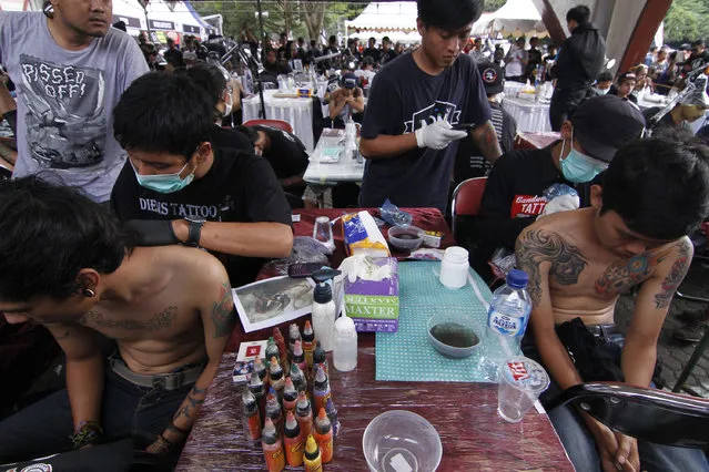 Some tattoo artists work on the visitors bodies during Bandung Body Art Festival at in Bandung, West Java, on December 7, 2014. (Photo by Rezza Estily/JG Photo)