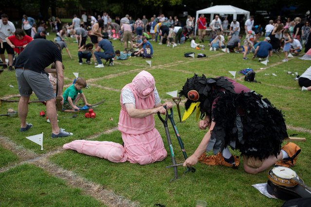 Chris White, dressed as a worm, and Andrew Feltham, dressed as a crow, compete in the annual World Worm Charming Championships held at Willaston Primary Academy in Willaston, near Nantwich, England on June 22, 2024. Held every year since 1980, the World Worm Charming Championships invites participants to employ various methods of vibration to charm as many worms from their plot of soil in half an hour. The Guinness World Record stands at 567 worms, with the winning team this year charming 195 worms in the 30 minutes. (Photo by Oli Scarff/AFP Photo)