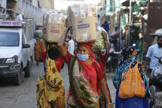 Indian women carry vegetables on their head at a vegetable market in Ahmedabad, India, Thursday, December 3, 2020. India is second behind the U.S. in total coronavirus cases. Its recovery rate is nearing 94%. (Photo by Ajit Solanki/AP Photo)