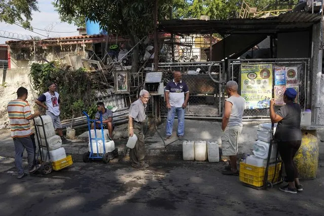 Locals wait for their turn to fill their water containers from water collected in an abandoned highway tunnel at the Cotiza neighborhood of Caracas, Venezuela, March 20, 2023. (Photo by Matias Delacroix/AP Photo)
