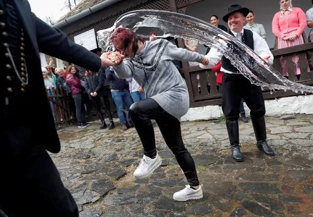 A woman reacts as men throw water at her during a traditional Easter celebration in Holloko, Hungary on April 10, 2023. (Photo by Bernadett Szabo/Reuters)