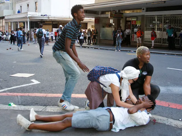 An injured student is helped by colleagues during protest outside the parliament during South African Finance Minister Pravin Gordhan's medium term budget speech in Cape Town, South Africa October 26, 2016. (Photo by Wayne Conradie/Reuters)