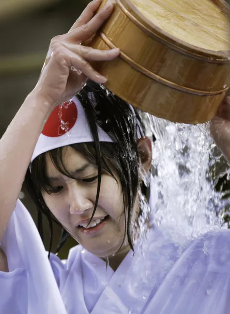 A shrine parishioner using a wooden tub pours cold water onto herself during an annual cold-endurance festival at the Kanda Myojin Shinto shrine in Tokyo, Saturday, January 10, 2015. (Photo by Eugene Hoshiko/AP Photo)