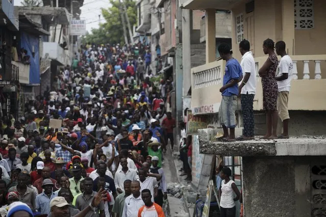 Residents watch protesters marching during a demonstration against the results of the presidential elections in Port-au-Prince, Haiti, November 26, 2015. (Photo by Andres Martinez Casares/Reuters)