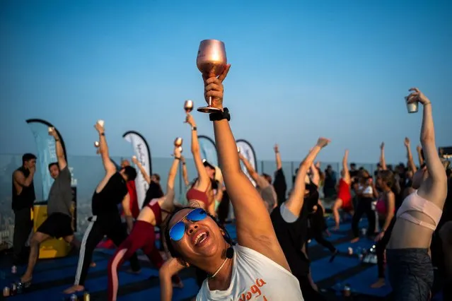 Yoga enthusiasts perform a yoga exercise in a Sunrise Wine Yoga class on the Mahanakhon Skywalk rooftop at the King Power Mahanakhon building in Bangkok, Thailand on April 8, 2023. (Photo by Athit Perawongmetha/Reuters)
