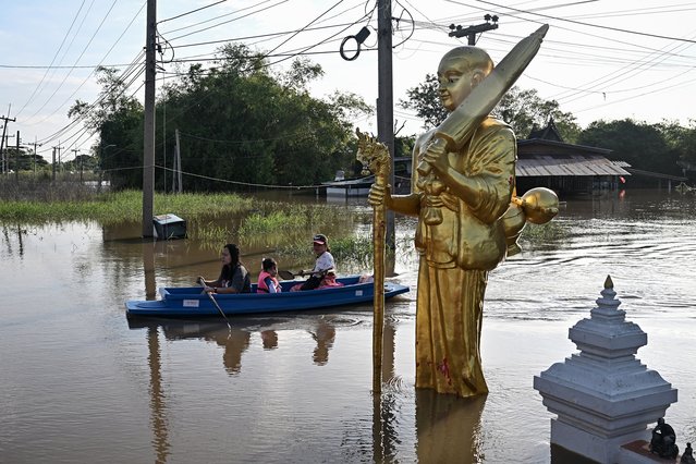 People take a boat from their flooded neighbourhood through the Wat Intharam Buddhist temple complex in Bang Ban district in the central Thai province of Ayutthaya on November 14, 2025. (Photo by Lillian Suwanrumpha/AFP Photo)