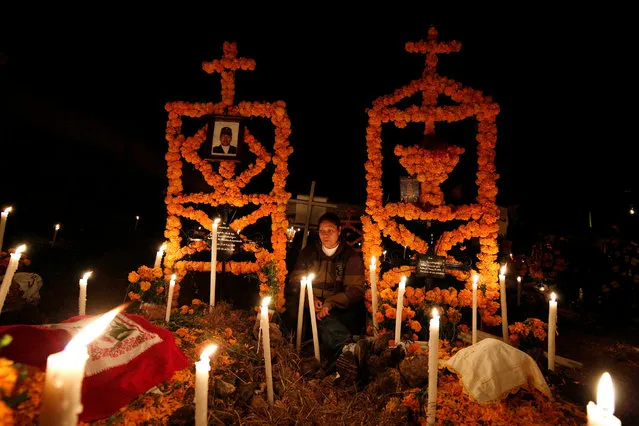 A woman sits among the tombs of her loved ones on the Day of the Dead at a cemetery in Arocutin, in Michoacan state, Mexico November 2, 2016. (Photo by Alan Ortega/Reuters)