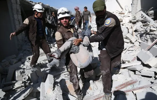 Syrian civil defense team members carry a wounded Syrian on the rubble of a collapsed building after the war crafts belonging to the Russian Army carried out airstrikes on the Ibin village of Aleppo, Syria on November 05, 2016. (Photo by Beha el Halebi/Anadolu Agency/Getty Images)