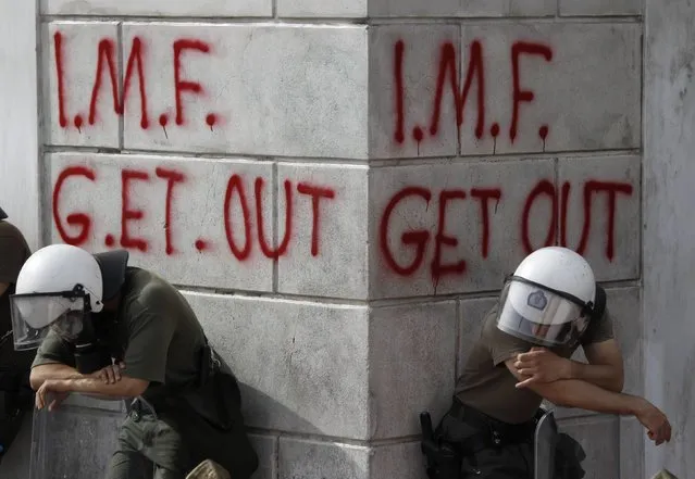 Greek riot policemen rest in front of graffiti written on the wall of a bank during violent demonstrations over austerity measures in Athens, in this May 5, 2010 file photo. (Photo by Yorgos Karahalis/Reuters)