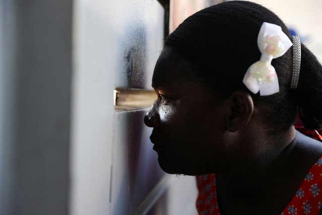 A Haitian woman peeks through an opening of a gate of a migration clearance centre where her husband had been taken, after the Dominican Republic said it would deport up to 10,000 migrants per week who were in the country illegally, in Santo Domingo, Dominican Republic on October 9, 2024. (Photo by Erika Santelices/Reuters)
