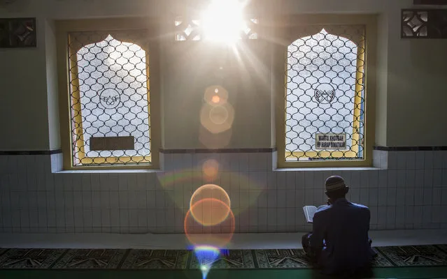 An Indonesian man reads Quran as he waits for the time to break his fast at a mosque in Solo, Central Java, Indonesia, Friday, July 12, 2013. During Ramadan, the holiest month in Islamic calendar, Muslims refrain from eating, drinking, smoking and s*x from dawn till dusk. (Photo by Gembong Nusantara/AP Photo)