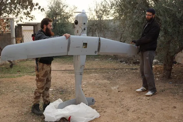 Muthanna Islamic Movement members inspect what they say is a Russian made military surveillance drone which they claimed to have shot down in Sheikh Meskeen near Deraa, Syria December 15, 2015. (Photo by Alaa Al-Faqir/Reuters)