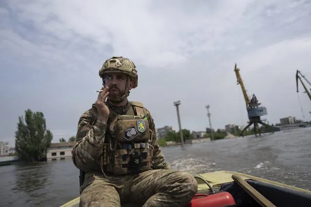 A Ukrainian serviceman steers a boat in a flooded neighborhood in Kherson, Ukraine, Thursday, June 8, 2023. Floodwaters from a collapsed dam kept rising in southern Ukraine on Wednesday, forcing hundreds of people to flee their homes in a major emergency operation that brought a dramatic new dimension to the war with Russia, now in its 16th month. (Photo by Evgeniy Maloletka/AP Photo)