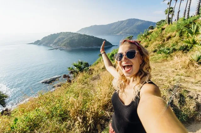 Young woman takes selfie, on hillside above sea. (Photo by Andrii Lutsyk/Ascent Xmedia GmbH via Getty Images)
