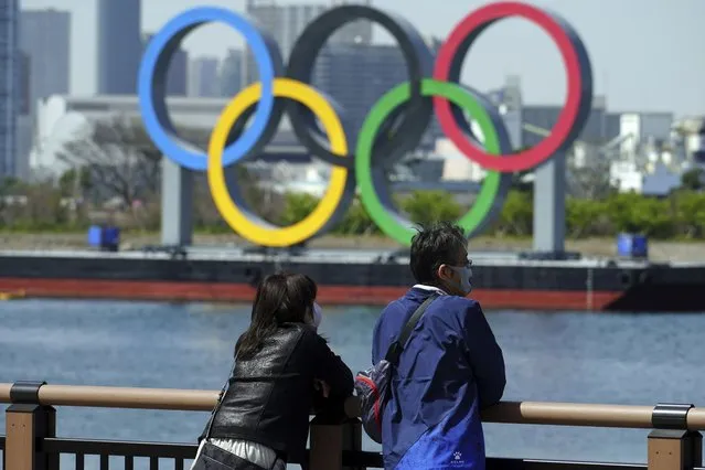 A man and a woman stand with a backdrop of the Olympic rings floating in the water in the Odaiba section Thursday, March 18, 2021, in Tokyo. Tokyo Olympics creative director Hiroshi Sasaki is resigning after making demeaning comments about Naomi Watanabe, a well-known female celebrity. Sasaki who was in charge of the opening and closing ceremonies for the Olympics, told planning staff members last year that Watanabe could perform in the ceremony as an “Olympig”. (Photo by Eugene Hoshiko/AP Photo)